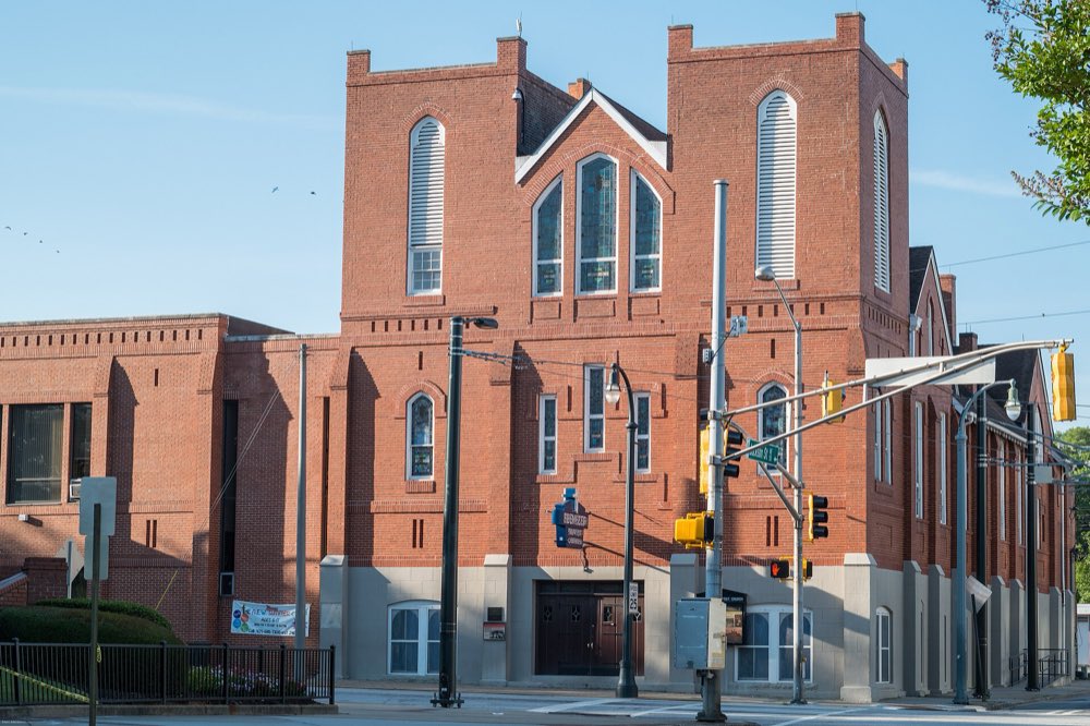 The red-brick twin towers of Historic Ebenezer Baptist Church on Auburn Avenue under a clear morning sky, with traffic lights at the corner