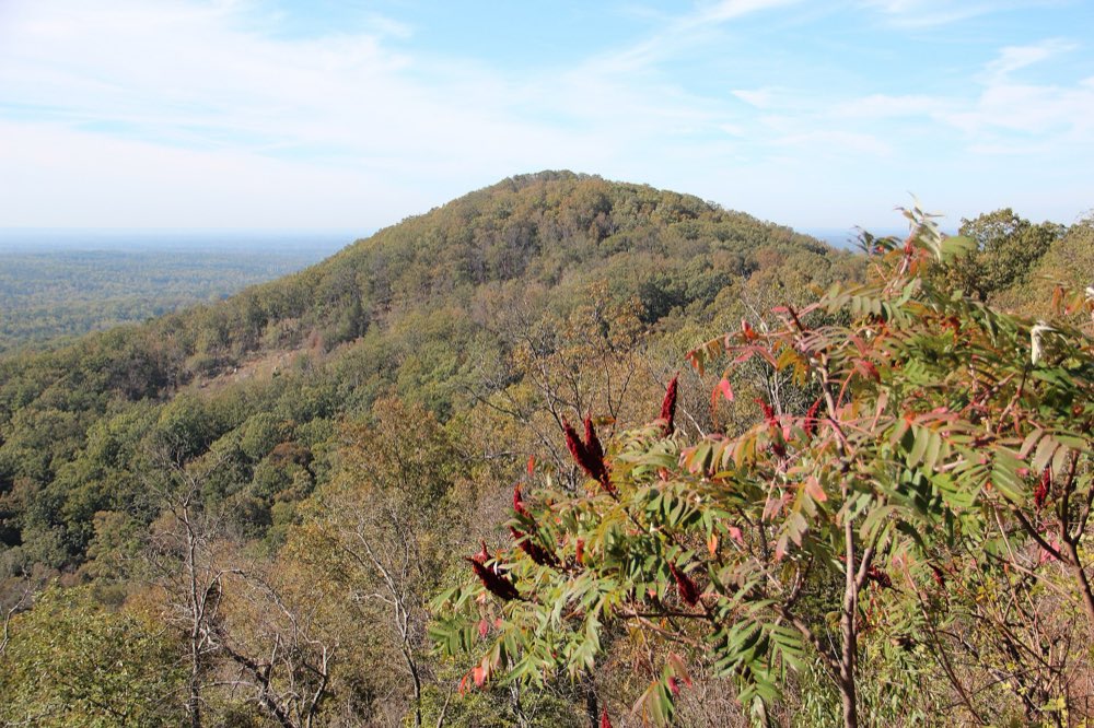Little Kennesaw Mountain seen from the top of Kennesaw Mountain, its wooded slopes turning red and gold in autumn under a pale blue sky