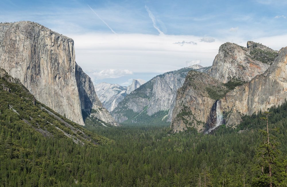 Yosemite Valley from Tunnel View: El Capitan's sheer granite wall on the left, Bridalveil Fall on the right, and Half Dome in the distance above a forested valley floor